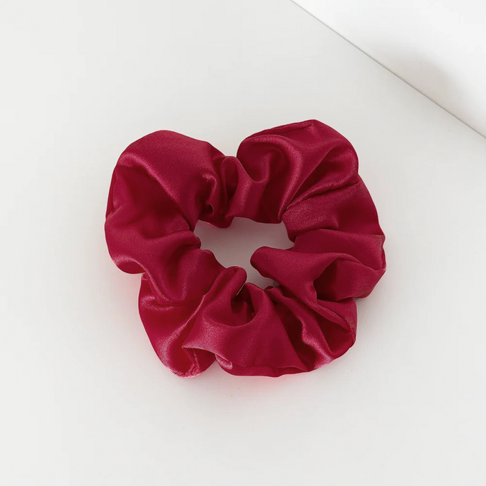 Burgundy satin scrunchie with a glossy finish shown on a white surface.