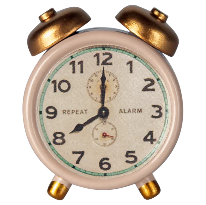 A small, traditional style alarm clock with a white face, black numbers, and gold-colored metal body.