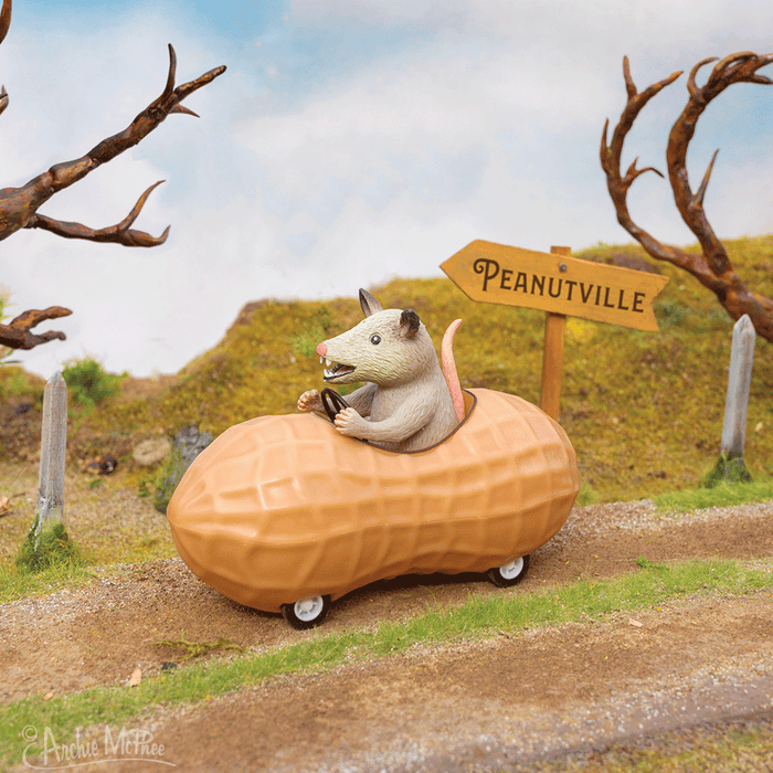 The Possum in a Peanut glides down a country road, zooming past a Peanutville sign amid the trees.