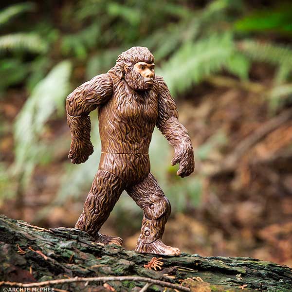This hard vinyl Bigfoot Action Figure depicts the legendary creature walking on a log in an authentic forest setting, reminiscent of classic Patterson film footage.