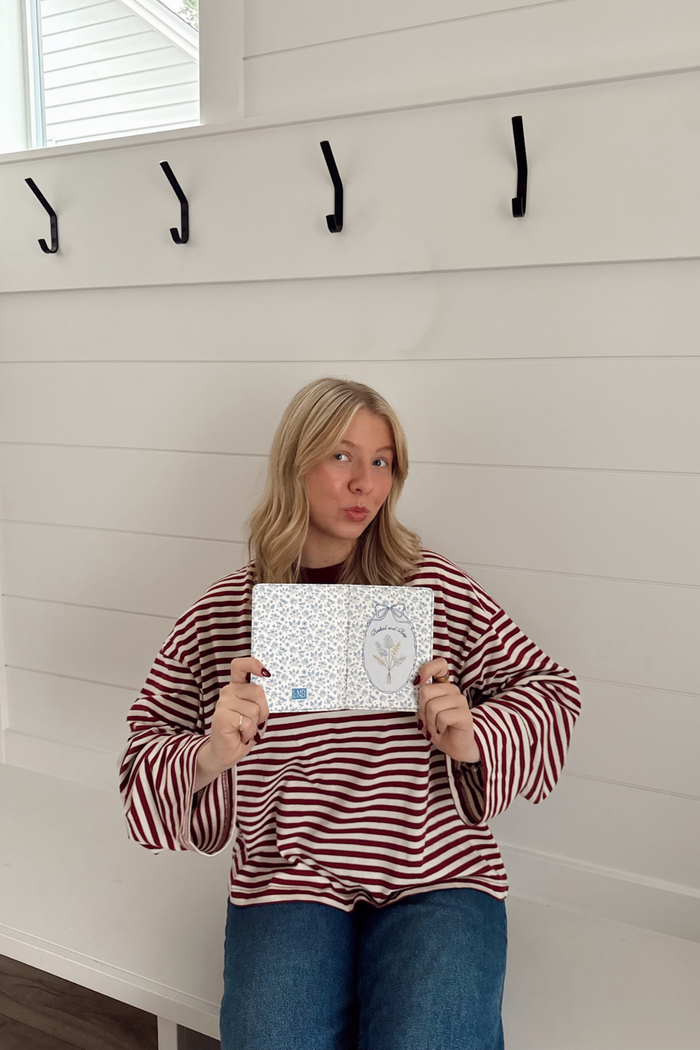 Person holding a book in front of a white wall with hooks