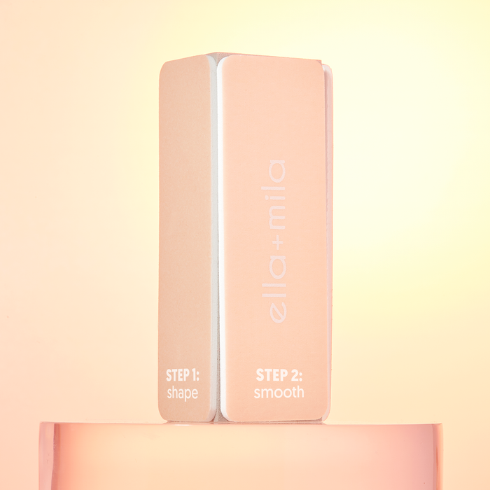 Peach nail buffer block standing upright on a peach background