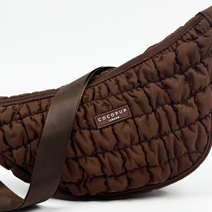 Brown crescent-shaped crossbody bag with wide strap by Coconut Lane, shown with matching dog walking accessories.