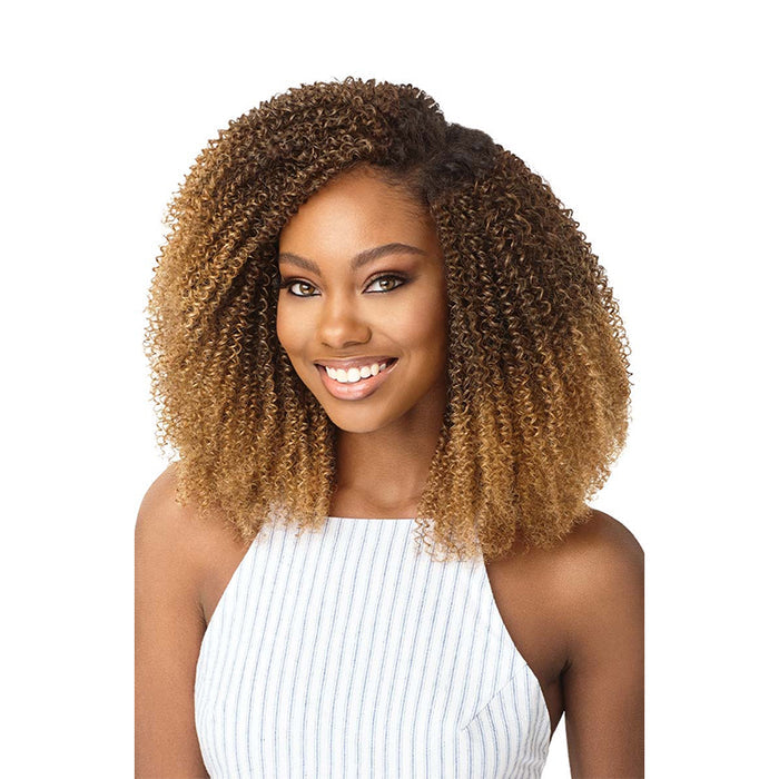 Smiling model wearing OUTRE 4C coily clip in hair extensions in honey blonde ombre with voluminous tight coils