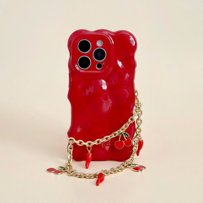Red wavy phone case with Coconut Lane Cherry Spice strap and cherry-shaped charms attached to a smartphone.