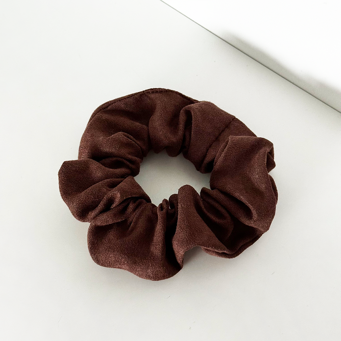 Chocolate brown suedette scrunchie from Coconut Lane on a white surface.