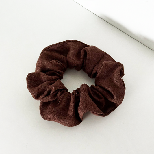 Chocolate brown suedette scrunchie from Coconut Lane on a white surface.