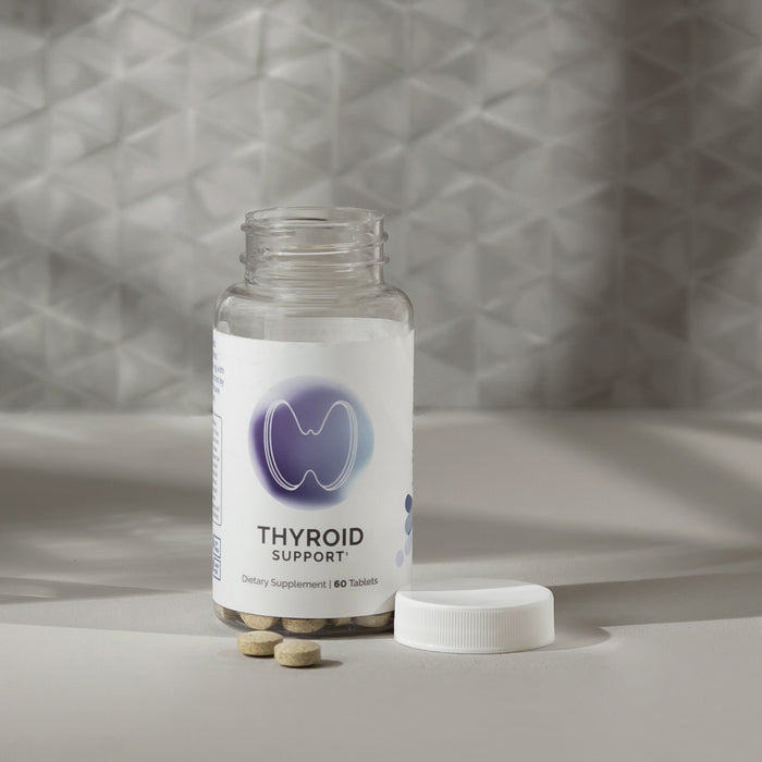 Infiniwell Thyroid Support supplement bottle with 60 tablets, open cap and tablets on light textured surface