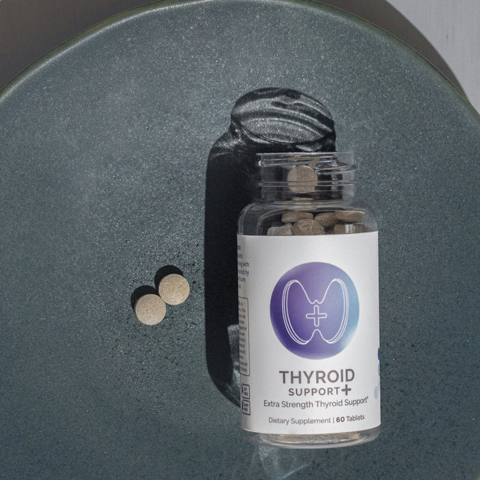 InfiniWell Thyroid Support+ Extra Strength dietary supplement bottle with tablets on dark textured surface, 60 tablets.