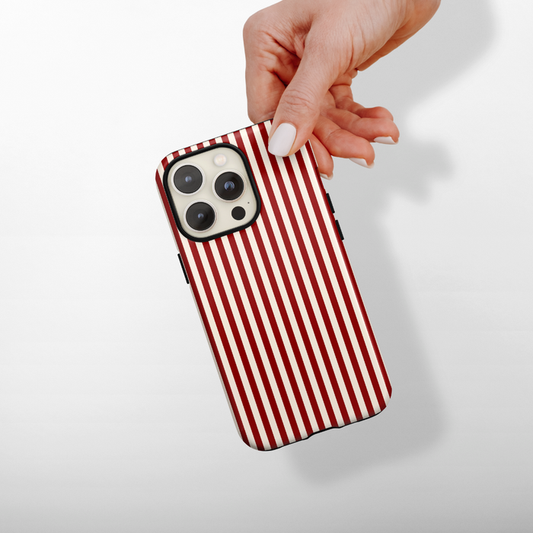 Hand holding a phone with a red and white striped Coconut Lane tough case, shown against a light background.