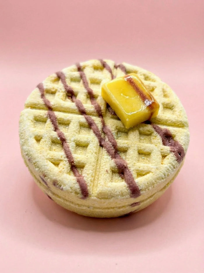 Waffle-shaped soap with faux butter pat on pink background, dessert-inspired bath product