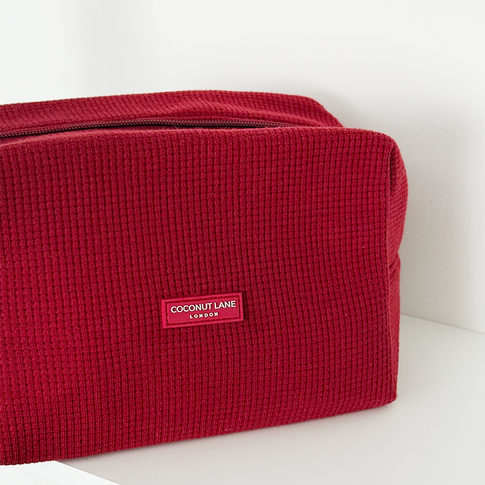 Burgundy Coconut Lane waffle-textured makeup bag on a white surface.